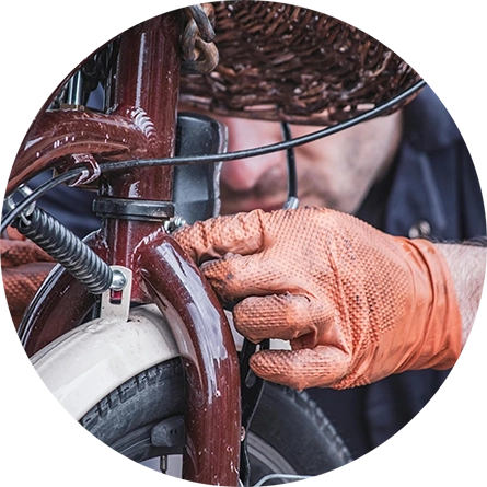A bicycle mechanic adjusting the breaks on a red bicycle.