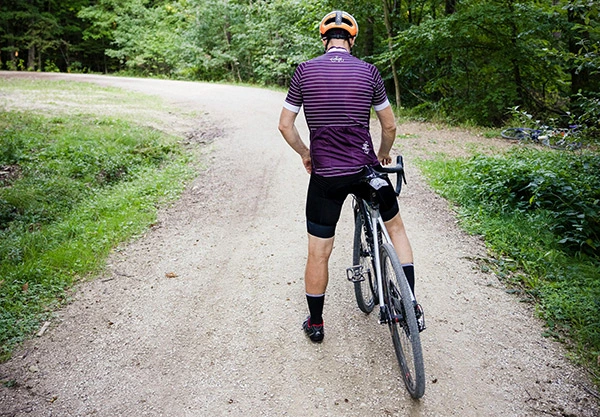 A man riding a gravel bike on a forested gravel path.