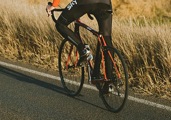 A man riding a Trek Domane road bike down a county road in a bike race outfit.